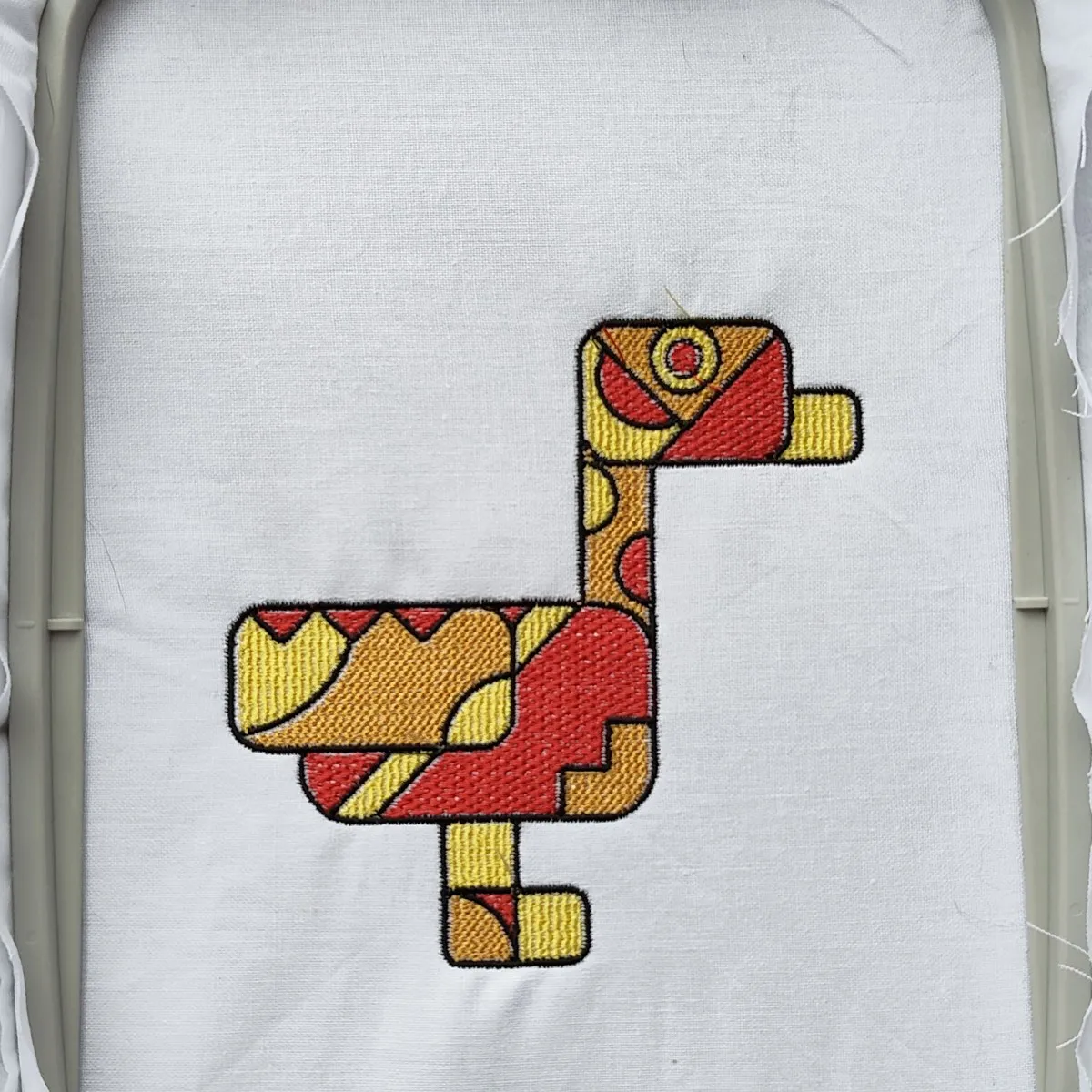 Geometric duck embroidered in red, orange and yellow thread in an embroidery hoop